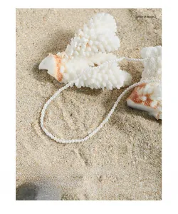 Detailed view of S925 silver pearl necklace on white coral and sand background