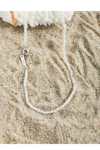 Detail of S925 silver clasp on elegant pearl necklace over natural sandy beach background
