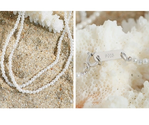 Macro shot of S925 sterling silver clasp and small pearl necklace on white coral