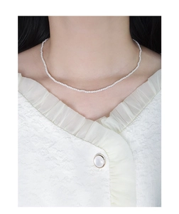 Detail of elegant S925 silver necklace with small white pearls on a model neck
