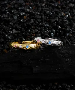 Détail de bagues en argent S925 avec texture plissée et zircons colorés sur fond de pierre noire