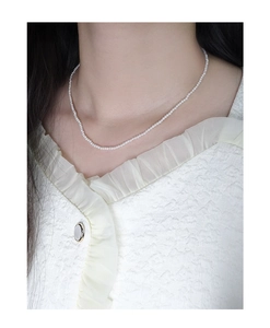 Detail view of a minimalist S925 silver pearl necklace worn on the neck for women