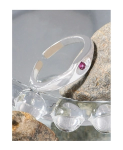 Macro shot of minimalist silver open ring with pink zircon on natural stone