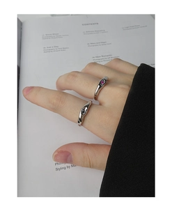Close-up of minimalist silver rings set with red gemstone on a lifestyle background