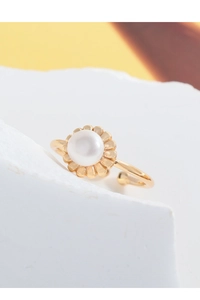 Macro detail of gold flower petal setting with a white pearl on a minimalist open ring