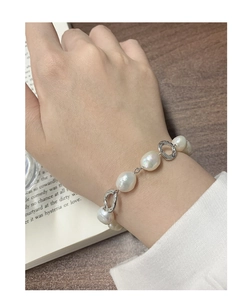 Detailed shot of baroque pearl bracelet with silver textured rings on female wrist