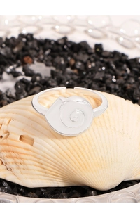 Macro shot of silver seashell spiral ring on a natural shell over black stones