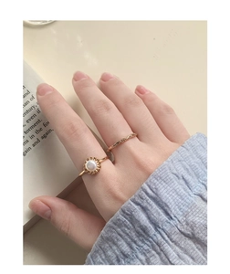 Detail of S925 silver flower pearl ring and twisted gold band worn on hand in cozy setting