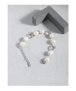 Detail of S925 silver bracelet with Baroque pearls and irregular metal rings on grey stone