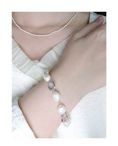 Close-up of Baroque pearl bracelet and fine pearl necklace on a white textured background