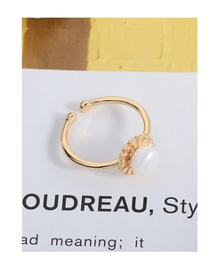 Close-up of a gold-plated flower bud ring with a central pearl and textured petal details