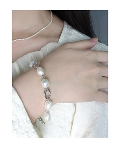 Close-up of Baroque pearl bracelet with silver ring details on woman's wrist