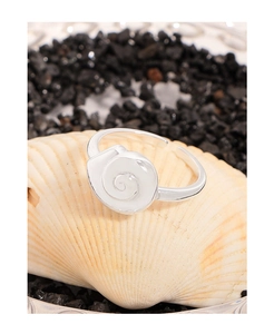 Macro detail of silver seashell open ring with textured spiral design on a shell