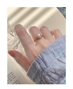 Close-up of a vintage pearl ring in gold flower setting worn on a finger
