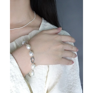 Elegant Baroque pearl bracelet and fine bead necklace set on a minimalist background