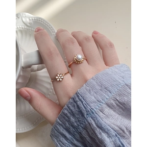 Elegant gold flower and pearl ring set on model's hand with soft lighting