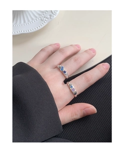 Detail of silver rings featuring blue and purple zircon gemstones on hand