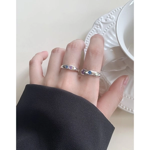 Silver S925 fluid rings set with colorful zircons on finger against white cup