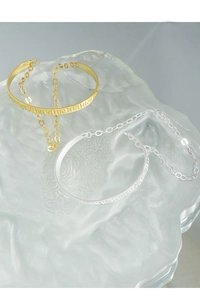 Close-up of gold and silver hammered texture chain bracelets on frosted glass