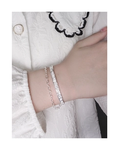 Detail of S925 sterling silver layered bracelet with textured cuff and chain on wrist