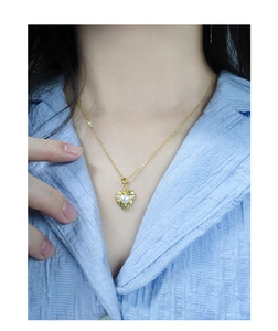 Detail of a heart-shaped pearl pendant with vintage hammered gold texture on a thin chain