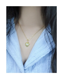 Detailed view of a gold heart pendant with crushed texture and center pearl on model