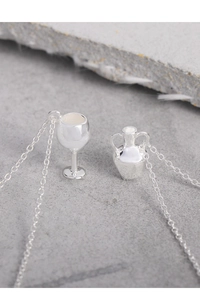 Macro shot of silver wine cup and amphora pendants on a fine O-chain necklace