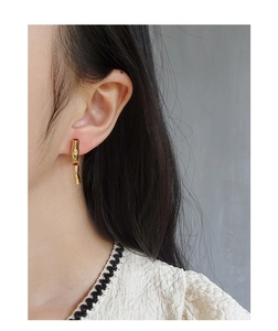 Close-up of elegant bamboo-shaped gold drop earrings on model with sleek metallic texture