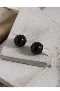 Macro detail of black agate bead earrings with silver leverback closure on stone
