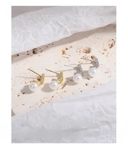 Detail of irregular geometric earrings with round pearls in gold and silver finish