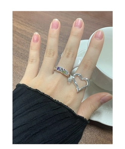 Detail of silver irregular heart ring and colorful gemstone band on a model hand