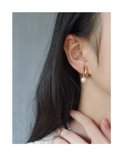 Detail of S925 silver asymmetric bamboo pearl earrings worn by a model on a grey backdrop