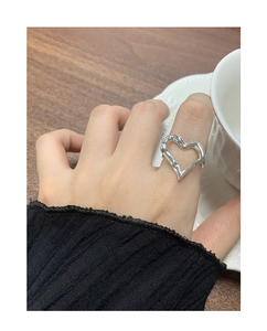 Detail view of large silver open heart ring with hammered texture on a woman finger