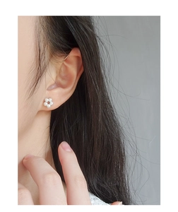 Close-up of a floral pearl stud earring featuring six white pearls in a delicate wreath