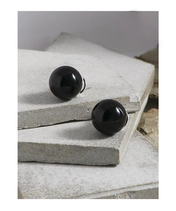 Macro shot of minimalist black onyx bead earrings on textured stone background