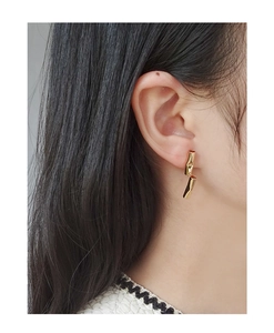 Close-up of asymmetric gold geometric drop earrings on model with high texture