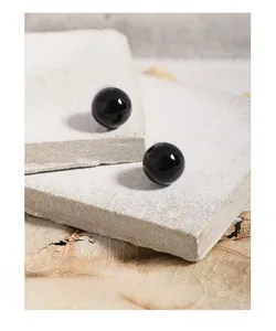 Detailed view of polished black agate bead earrings on natural stone and autumn leaf