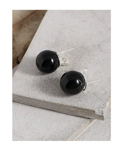 Detailed close-up of S925 silver stud earrings with polished black onyx spheres on stone