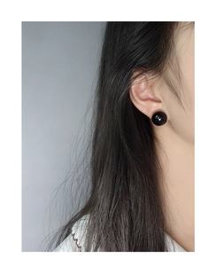 Close-up of minimalist black agate round stud earrings on a model showing sleek texture