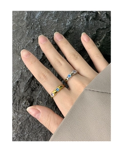 Detail of gold and silver S925 rings with blue and purple zircons on stone background