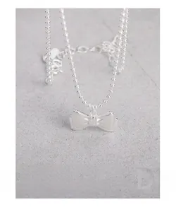 Macro shot of S925 sterling silver bow pendant necklace with polished beaded chain detail