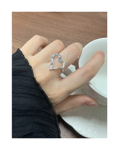 Detailed view of silver heart-shaped irregular liquid metal ring worn on finger