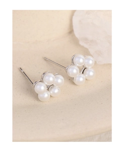 Detailed view of silver floral pearl earrings arranged on a textured stone tray