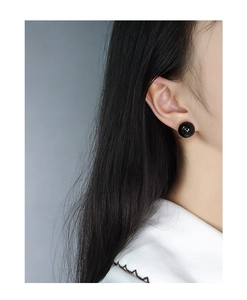 Close-up of a model wearing black minimalist spherical stud earrings in a polished finish
