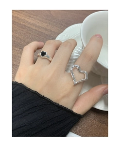 Detailed view of silver heart rings with hammered texture and black enamel on wood background