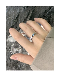 Macro detail of textured silver ring featuring square blue and round purple gemstones