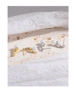 Detailed view of irregular geometric pearl earrings on a textured stone background