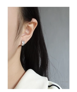 Detail of silver S925 heart zircon hoop earrings shown worn on an ear model