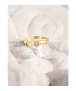 Close-up of gold adjustable ring featuring hammered texture and colorful zircon stones