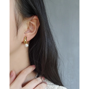 Elegant bamboo-shaped gold earrings with white pearls shown on a female model